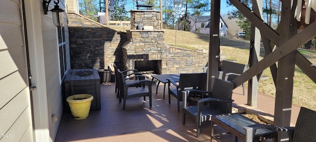 view of patio featuring an outdoor stone fireplace and a deck