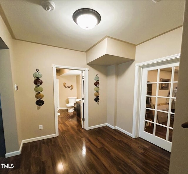 corridor with ornamental molding, baseboards, and wood finished floors