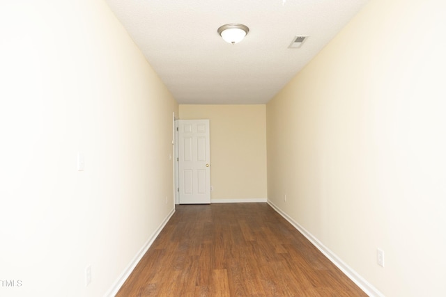 corridor featuring baseboards, visible vents, and wood finished floors