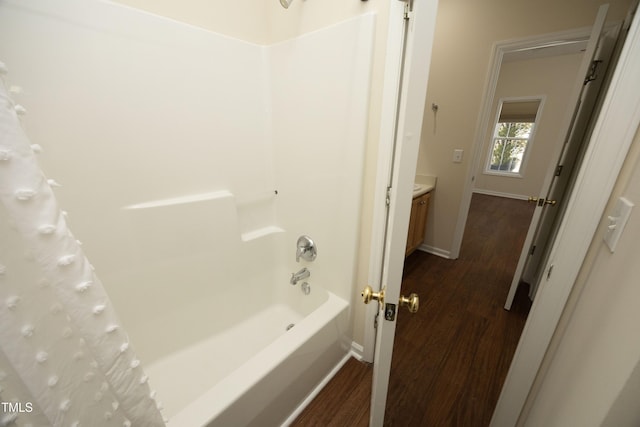 full bathroom featuring shower / bath combo, vanity, baseboards, and wood finished floors