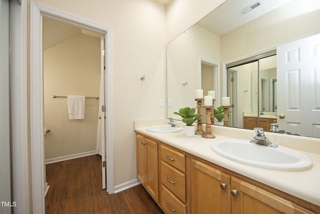 full bathroom featuring double vanity, visible vents, a sink, and wood finished floors