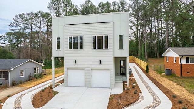 view of front of home with a garage, central air condition unit, driveway, and fence