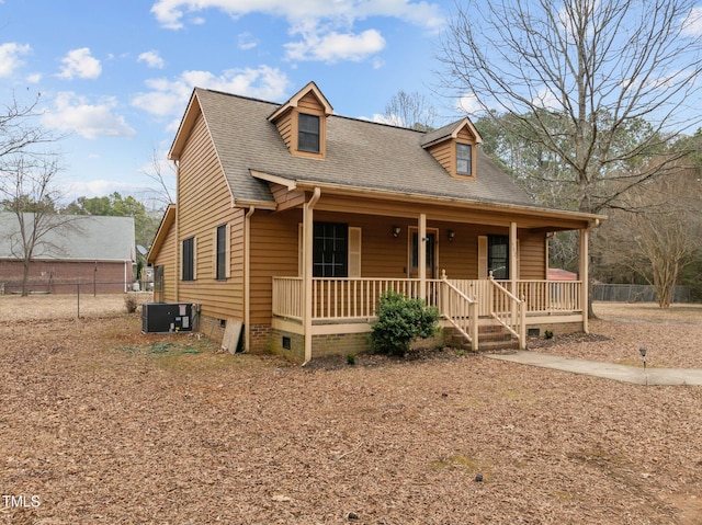 view of front facade with a porch, crawl space, a shingled roof, and fence