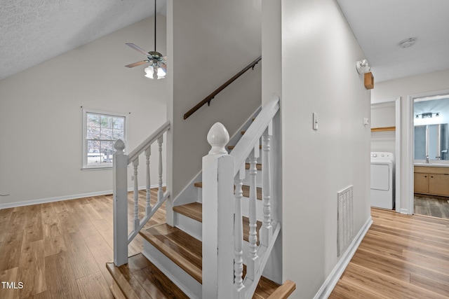 stairway featuring ceiling fan, wood finished floors, visible vents, baseboards, and washer / dryer