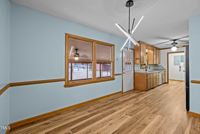 kitchen with a sink, light countertops, stainless steel dishwasher, light wood finished floors, and brown cabinetry