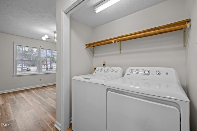 clothes washing area with washer and dryer, a textured ceiling, baseboards, and wood finished floors