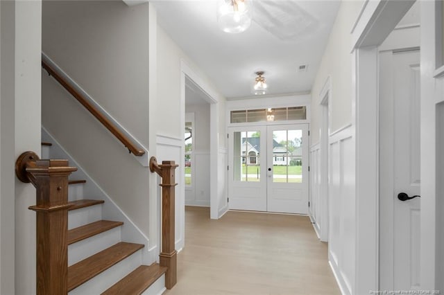 foyer with stairs, light wood finished floors, french doors, and visible vents