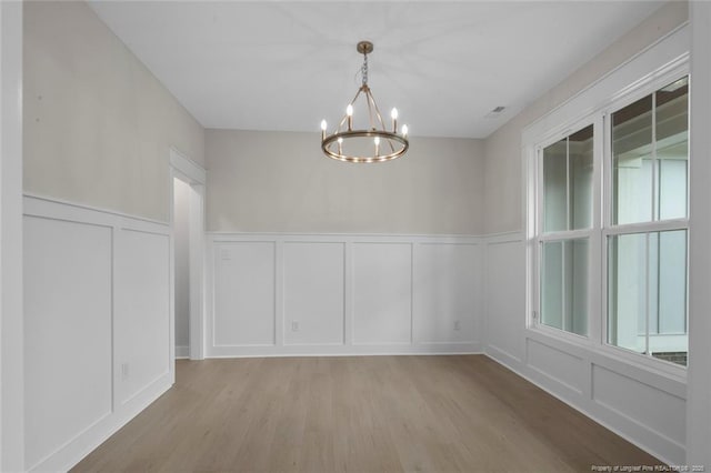 interior space featuring a chandelier, light wood-type flooring, and a decorative wall