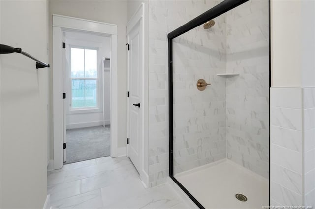 bathroom with marble finish floor, baseboards, and a stall shower