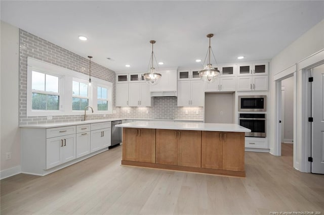 kitchen featuring decorative backsplash, appliances with stainless steel finishes, a center island, and light wood-style floors