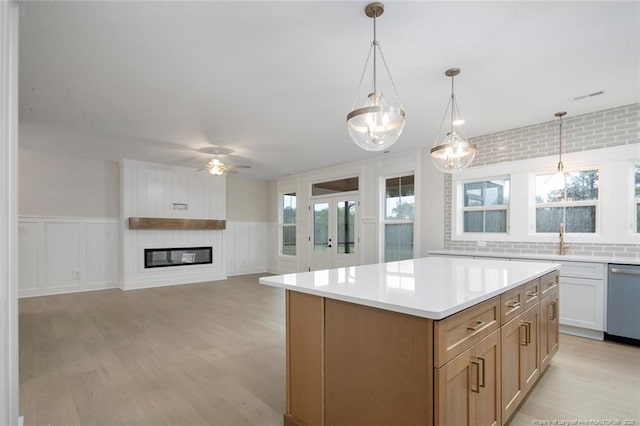 kitchen with a center island, light countertops, a ceiling fan, light wood-style floors, and stainless steel dishwasher
