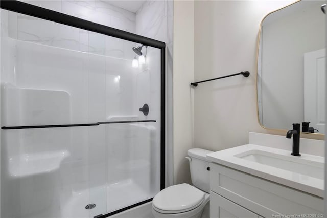 bathroom featuring toilet, a shower stall, and vanity