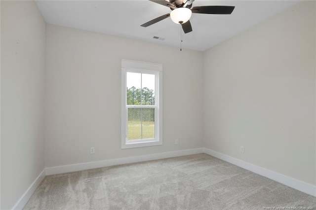 carpeted spare room with visible vents, baseboards, and ceiling fan