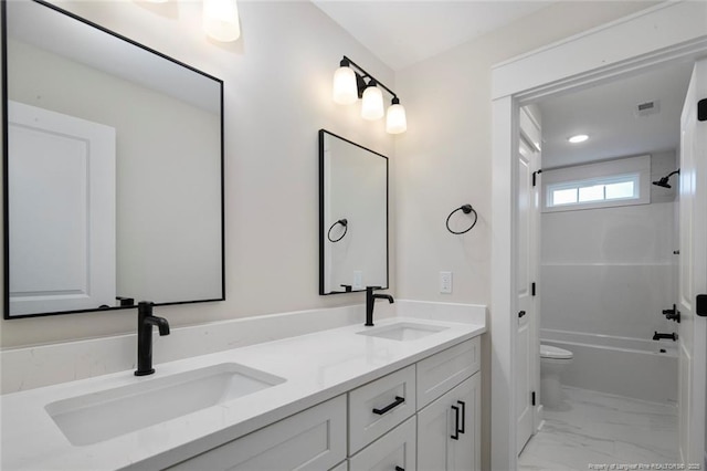 full bath with toilet, double vanity, marble finish floor, and a sink