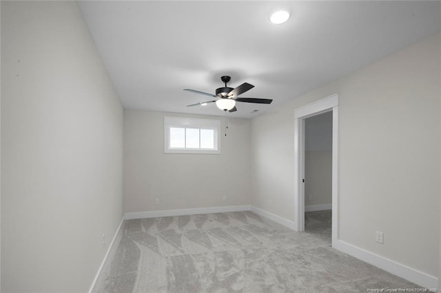 empty room featuring light carpet, baseboards, and a ceiling fan