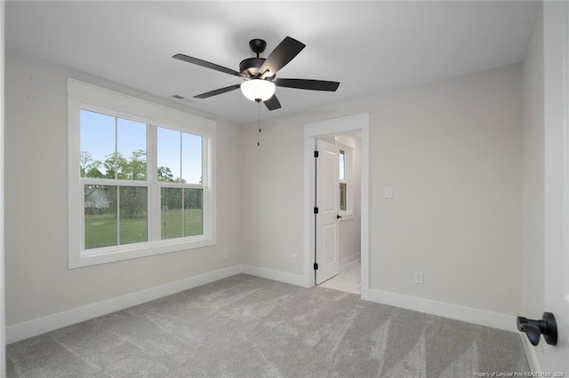 carpeted empty room with baseboards and a ceiling fan