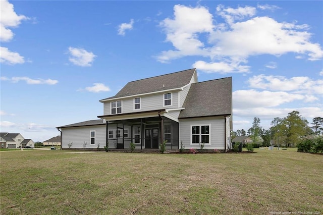 rear view of property with a yard, a sunroom, and a shingled roof