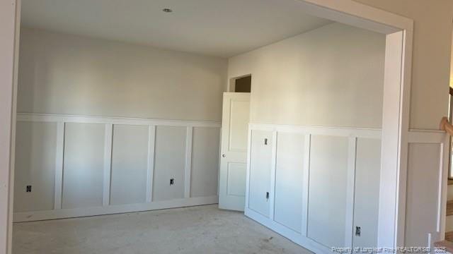 unfurnished bedroom featuring a wainscoted wall and a decorative wall