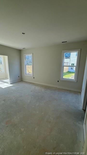 unfurnished room featuring baseboards, visible vents, and unfinished concrete floors