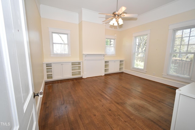 spare room featuring ornamental molding, dark wood-style flooring, a ceiling fan, and a healthy amount of sunlight