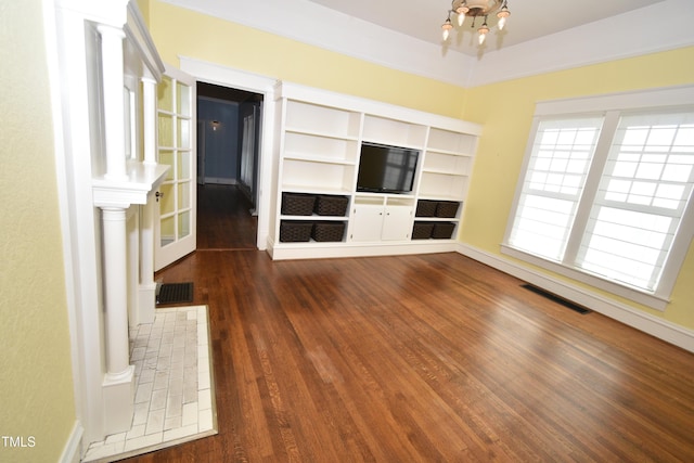 unfurnished living room featuring ornate columns, a notable chandelier, visible vents, and wood finished floors