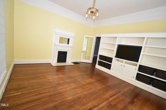 unfurnished living room featuring baseboards, a fireplace, dark wood finished floors, and an inviting chandelier