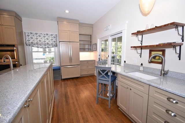 kitchen featuring paneled refrigerator, double oven, open shelves, and a sink