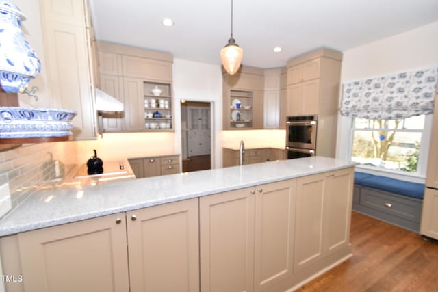 kitchen with open shelves, a peninsula, wood finished floors, and light stone countertops