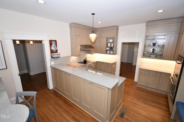 kitchen featuring dark wood-type flooring, a peninsula, under cabinet range hood, open shelves, and a sink