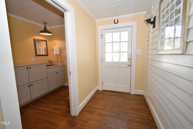 doorway with ornamental molding, a sink, dark wood finished floors, and baseboards