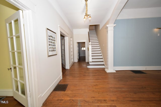 entryway featuring wood finished floors, visible vents, baseboards, stairs, and ornate columns