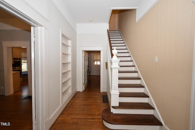 stairway featuring built in features, visible vents, baseboards, and wood finished floors