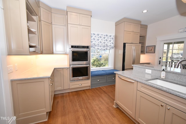 kitchen featuring double oven, plenty of natural light, a sink, and refrigerator