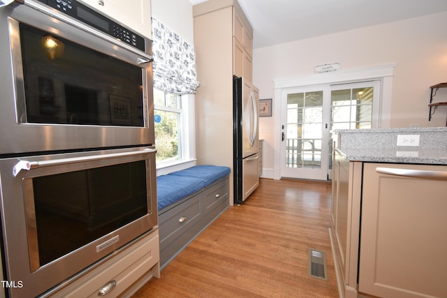 kitchen featuring light wood-style flooring, visible vents, appliances with stainless steel finishes, and light stone counters