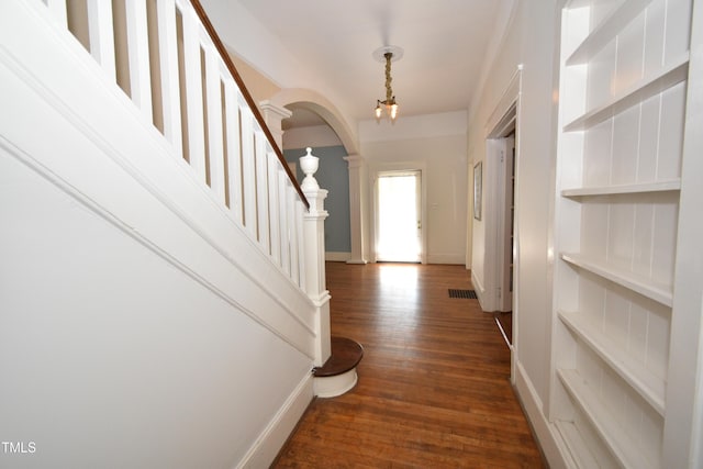 foyer featuring dark wood-style floors, arched walkways, visible vents, baseboards, and stairs