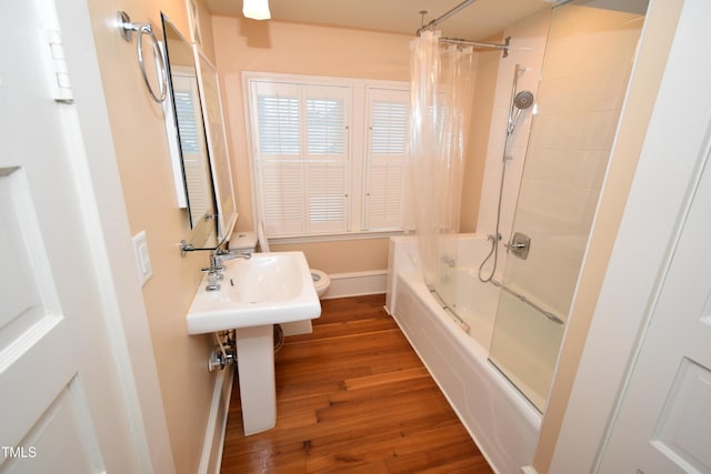 full bath with wood finished floors, shower / bath combo with shower curtain, toilet, and baseboards