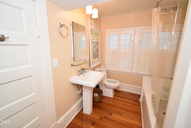 full bath with curtained shower, wood finished floors, toilet, and baseboards