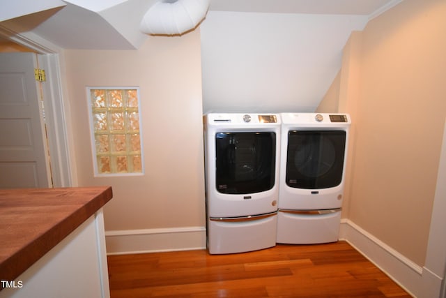 washroom with laundry area, independent washer and dryer, wood finished floors, and baseboards