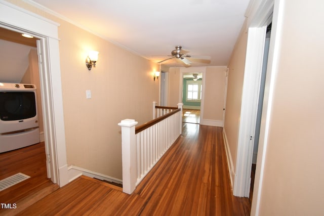 corridor featuring visible vents, washer / clothes dryer, wood finished floors, and an upstairs landing