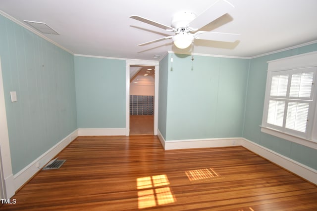 spare room with visible vents, crown molding, and wood finished floors