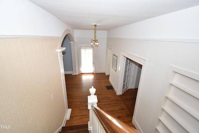 interior space with built in shelves, arched walkways, dark wood-style flooring, a notable chandelier, and lofted ceiling