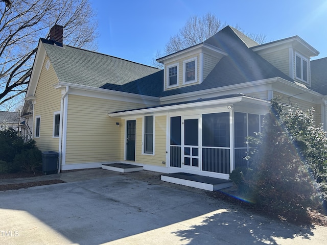 view of front of property featuring a sunroom and a shingled roof