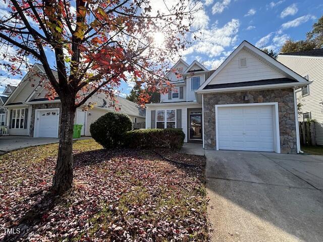 view of front of home featuring a garage, stone siding, and driveway