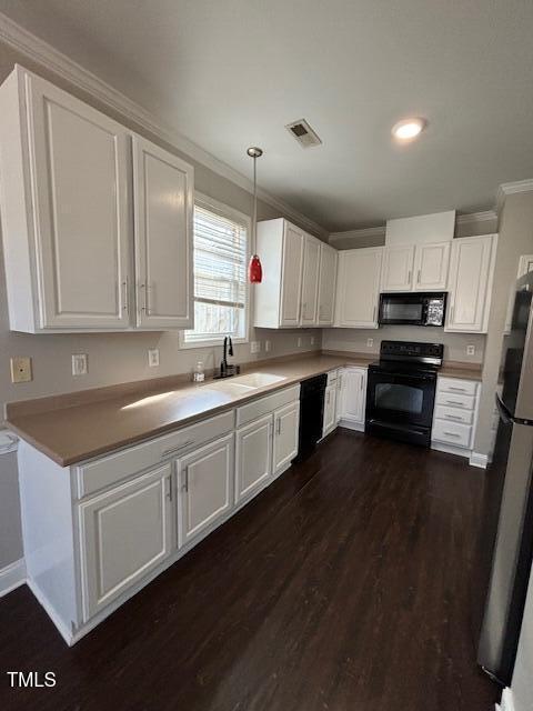 kitchen with black appliances, crown molding, white cabinets, and a sink