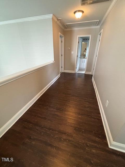 corridor with baseboards, wood finished floors, attic access, and crown molding