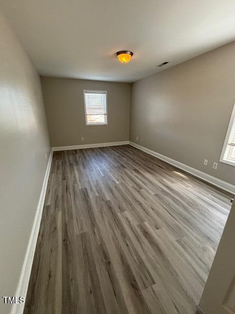 spare room featuring wood finished floors, visible vents, and baseboards