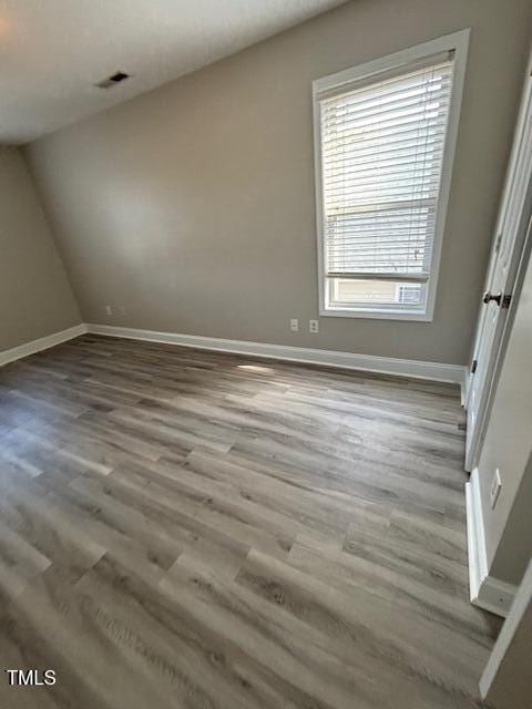 unfurnished bedroom with visible vents, baseboards, vaulted ceiling, and wood finished floors