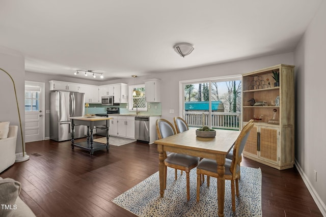 dining space with a healthy amount of sunlight, dark wood finished floors, and baseboards