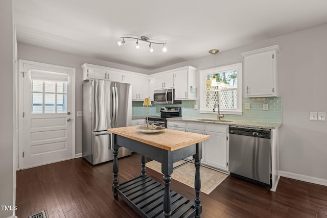 kitchen with appliances with stainless steel finishes, a sink, dark wood finished floors, and white cabinets