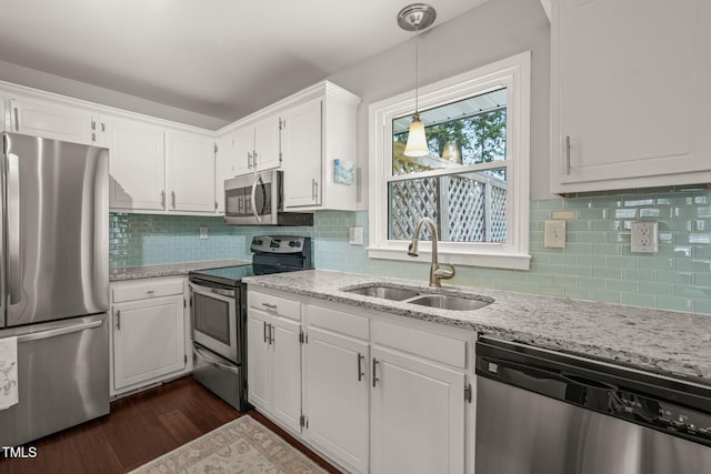 kitchen featuring stainless steel appliances, a sink, white cabinetry, light stone countertops, and dark wood-style floors